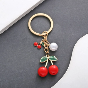 Macro view of red cherry keychain with gold metal plating and white pearl detail