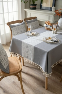 Detail of grey and beige Christmas deer jacquard tablecloth with festive fringe tassels