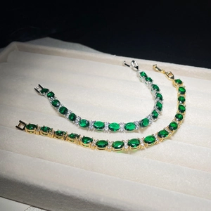 Detail of emerald green zircon bracelets in gold and silver finish on jewelry tray