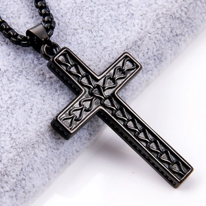 Detailed view of black stainless steel cross pendant with heart cutout on gray velvet