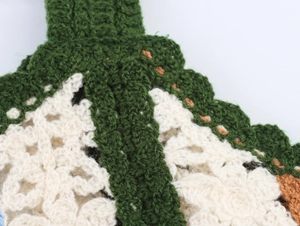 Close-up of handmade crochet embroidery detail on the knitted camisole top in green and beige