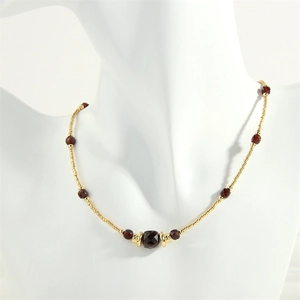 Detail of beaded necklace with gold spheres and faceted deep red garnet gemstones
