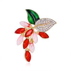 Detail of flower brooch with red petals, green enamel leaves, and crystal rhinestones