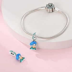 Detailed view of silver charm bracelet featuring blue and green cartoon pendant and clover clasp