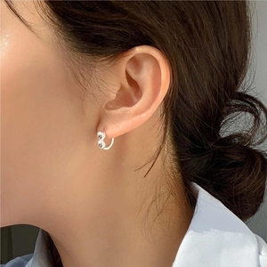 Detail view of a 925 sterling silver ball earring worn on ear with minimalist style