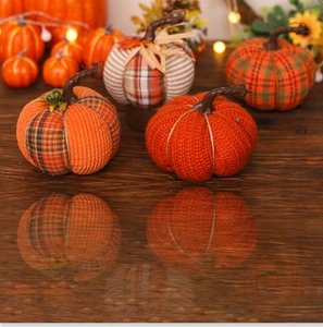 Macro shot of colorful knitted and plaid fabric pumpkins with realistic wooden stems