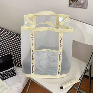 Mesh laundry bag with 'A Better Life' text and reinforced beige handles on a chair