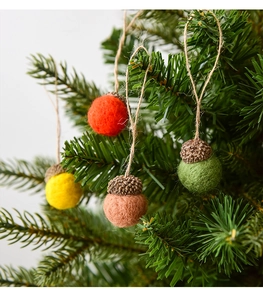 Close-up of wool felt acorn ornaments in natural colors hanging on Christmas tree branches