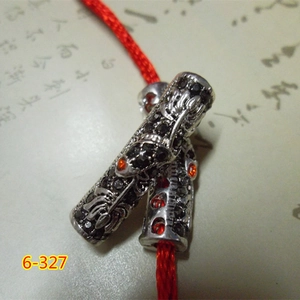 Macro view of vintage alloy tube beads with orange stones on a red braided cord