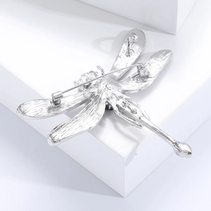 Close-up of a silver dragonfly brooch featuring detailed metal texture and a secure pin back