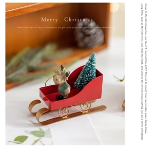Close-up of a decorative red and gold Christmas sleigh with a miniature tree and reindeer