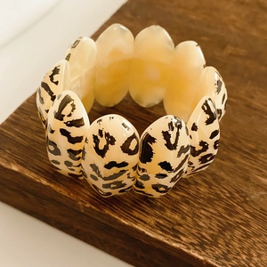 Close-up of leopard print resin oval link stretch bracelet on a dark wooden base