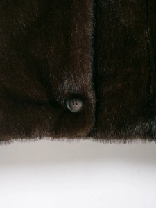 Detailed close-up of dark brown faux fur texture and a natural grain four-hole button