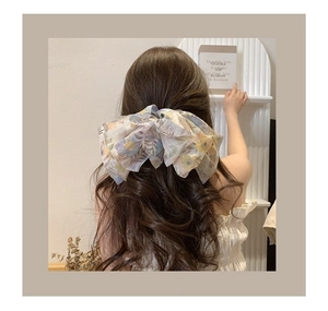 Barrette à cheveux avec nœud en mousseline florale portée pour un look féminin léger