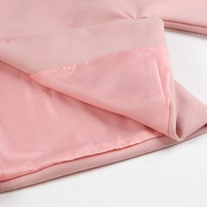 Détail d'un manteau en laine rose montrant le tissu texturé et la doublure en soie