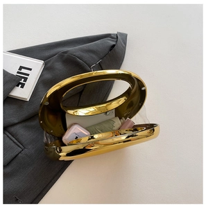Bolso de mano acrílico espejo dorado con asa redonda sobre un blazer gris