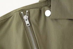 Détail du tissu sergé vert olive avec fermeture éclair métallique et bouton argenté