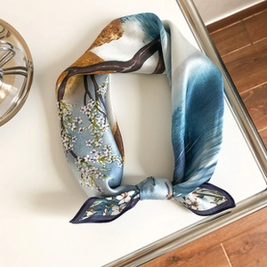 Detail of silk scarf with blue and white floral pattern tied in a knot on wooden surface