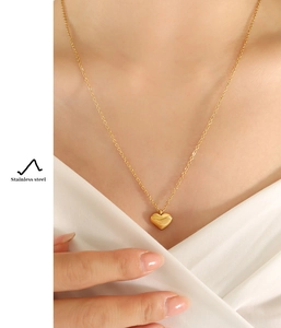 Polished heart-shaped pendant necklace in gold-plated stainless steel on female neck