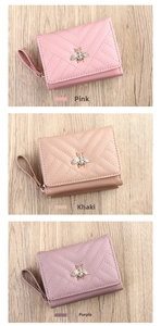 Three folded women wallets in pink, khaki and purple with bee detail on wooden background