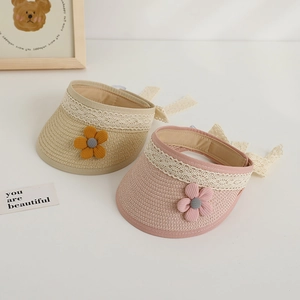 Detail of woven straw kids sun visor with lace trim and delicate floral decorations