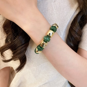 Detail of dark green glitter beads and gold geometric spacers on an elastic bracelet