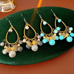 Close-up of bohemian bronze teardrop earrings with turquoise and marble beads