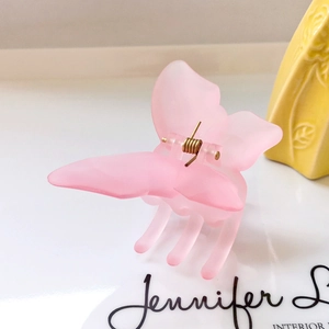 Detail of pink matte butterfly hair claw clip with golden spring on ceramic display