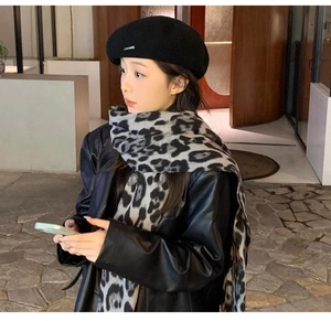 Classic leopard pattern scarf and black beret worn by a model in a stylish night city setting