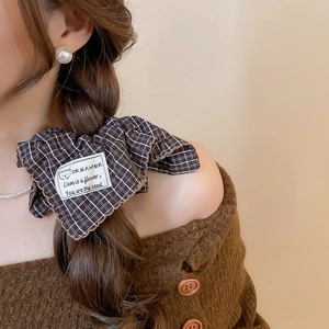 Detailed close-up of dark brown plaid fabric scrunchie with cute bear embroidery patch