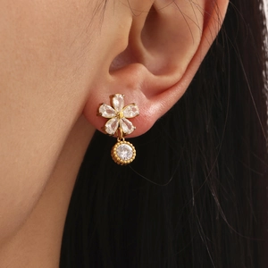 Boucles d'oreilles fleur en acier doré 18k et zircon 5A portées par un mannequin