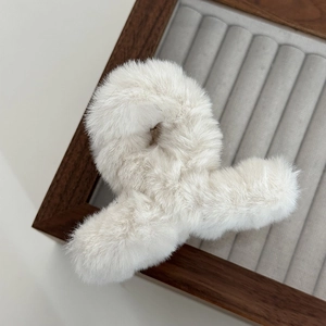 Detailed view of plush white faux fur hair claw clip on elegant velvet display tray