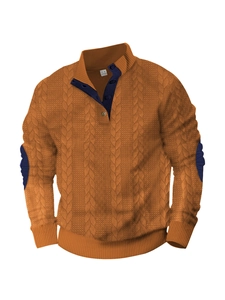 Dettaglio della maglia a trecce e toppe sui gomiti a contrasto sul maglione arancione