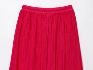 Détail de la jupe midi rose fuchsia montrant la texture plissée et la taille élastique