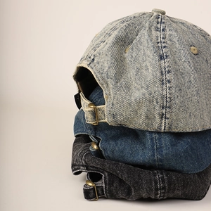 Detail of vintage washed denim baseball caps showing adjustable metal buckles and texture
