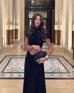 Detail of elegant black mesh dress with cross pleats and luxury leather handbag