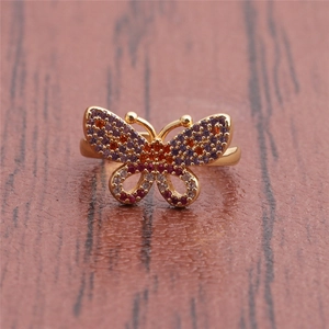 Detailed view of a gold-tone butterfly ring set with purple and orange cubic zirconia