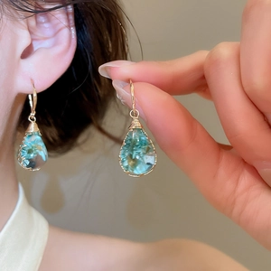 Detail macro view of handmade dried flower resin teardrop earrings, soft blue floral design