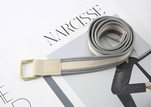 Close-up of gray and beige striped canvas belt with double ring buckle on a magazine