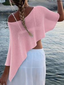 Detailed back view of a pink knit asymmetric poncho cover-up on a sunny beach