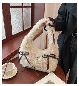 Dettaglio borsa a spalla in peluche crema con fiocchi marroni in un set invernale