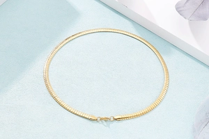 Detailed view of a sleek golden herringbone chain necklace with smooth metallic luster