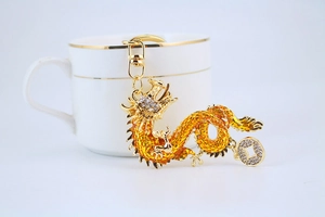 Detail of golden dragon keychain with orange enamel and sparkling crystal rhinestones