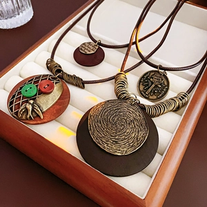 Détail de colliers vintage en cuir avec pendentifs en laiton et perles en bois sur plateau