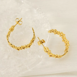 18K gold hollow star hoop earrings with polished finish on a white textured background