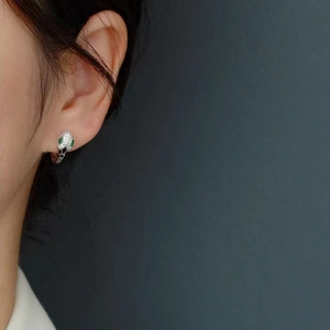Close-up of S925 sterling silver snake earrings with diamonds and green gem eyes