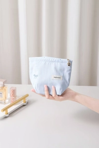 Détail de la trousse de maquillage à rayures bleues avec broderie et zip fleurie