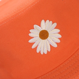 Orange cotton bucket hat featuring detailed white daisy embroidery and twill texture