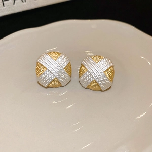 Dettaglio macro di orecchini a bottone circolari bicolore oro e argento su ceramica