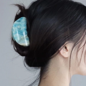 Artistic blue and white marble pattern resin hair claw clip shown on a model
